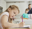 © Mint Images - Girl sitting at table in family kitchen, doing her homework