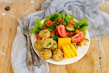 Polenta grill with chicken meatballs and fresh vegetables on a w