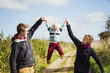 © Mint Images - Parents holding a small boy's hands and lifting him up in the air.