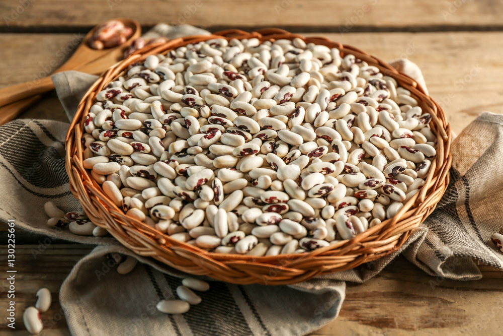 White beans in wicker basket and napkin on wooden table