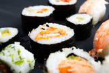 Fototapeta Kwiaty - Japanese sushi on black kitchen slate plate.