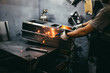 © hedgehog94 - Factory for production of heavy pellet stoves and boilers. Close up shot of manual worker's hand welding some parts.