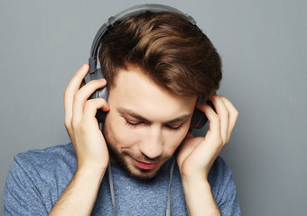  Happy young stylish man  adjusting his headphones ad smiling wh