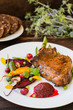 © mahara - Fried Grilled pork steak on the bone with vegetables, mashed beetroot and berry sauce. Wooden background. Top view. Close-up