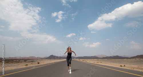 Photographie Young happy woman on an empty road in Oman desert.