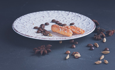 a sugar cookies on a vintage saucer with ornament spice anisetree and cardamom on a dark surface haze filter