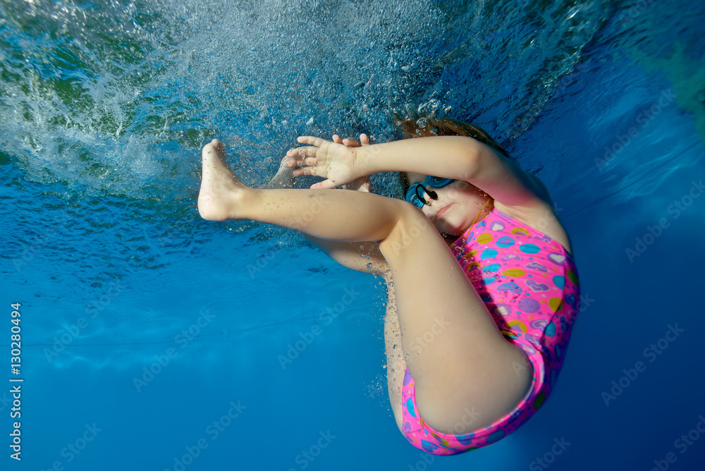 unde young little girls Little girl underwater in the pool plays sports on a blue background, floats and tumbles. Portrait. Close-up. The view from under the water at the bottom. Landscape orientation の Stock フォト |