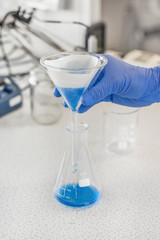 Laboratory technician performs tests and pouring blue liquid