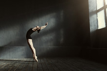 Flexible Ballet Dancer Stretching In The Dark Lighted Studio