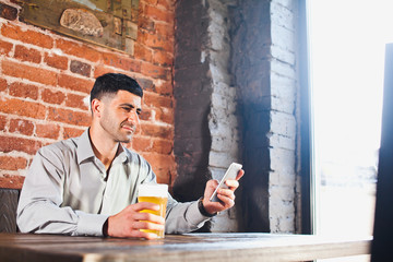 Businessman with beer in bar checking phone