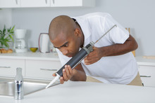 Man Sealing Around Kitchen Sink