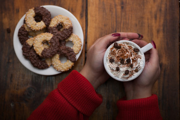 Female hands holding cups of coffee on rustic wooden table backg