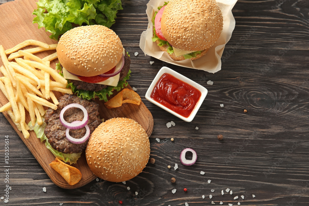 Delicious burgers and snacks on wooden background