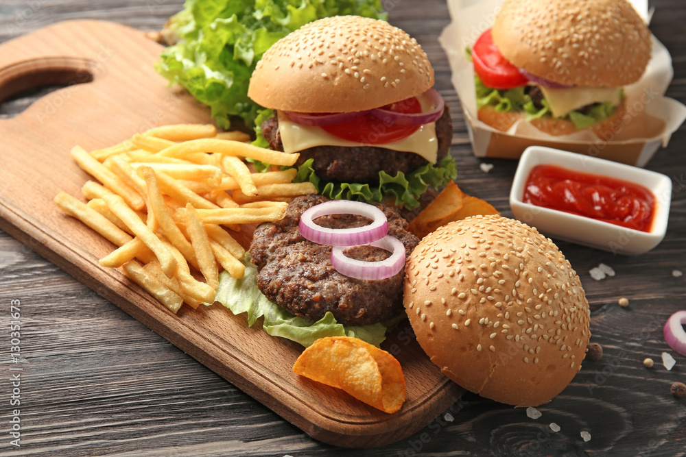 Delicious burgers and snacks on wooden table closeup