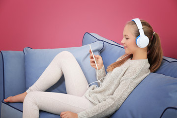 Wall Mural - Cute teenager with smart phone sitting on sofa in room