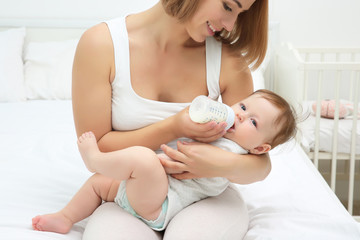 Wall Mural - Mother holding and feeding baby from bottle