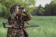 © fStop - Hunter looking through binoculars on grassy field