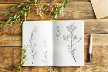 Sticker - collection of plants and sketchbook with drawings on wooden background