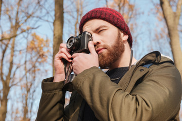 Poster - Bearded man using camera standing in the forest.