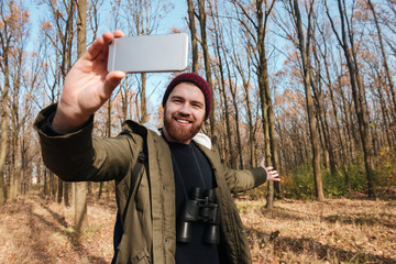 Wall Mural - Happy man making selfie by the phone in the forest