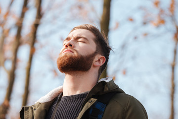 Poster - Relaxed bearded man standing in the forest with eyes closed.