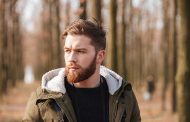 Handsome bearded man standing in the forest.