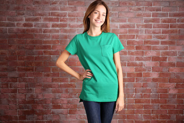 Canvas Print - Young woman in blank green t-shirt standing against brick wall