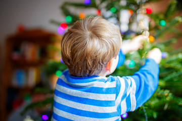 Wall Mural - Cute little kid boy decorating Christmas tree with colorful balls