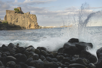 Deep blue sea waves splashing volcanic rocks, Aci Castello in ba