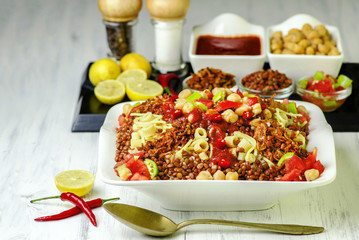 Arabic cuisine, Traditional Egyptian food: Koshary of rice, pasta, chickpeas, lentils,crispy onion and tomato sauce on white plate..