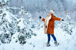 Young pregnant woman wearing warm clothes having fun on winter forest