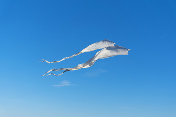 Two white kites flying high in the blue sky