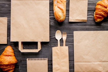 Wall Mural - cup coffee and bread in paper bag on wooden background