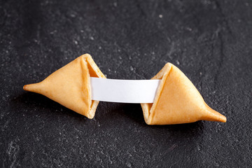 Chinese fortune cookie with prediction on dark background top view