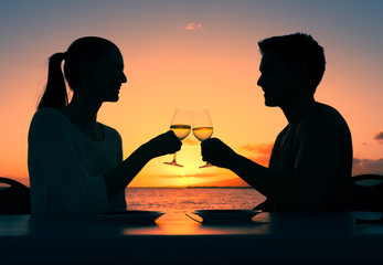 Romantic dinning. Young couple enjoying a glass of wine in a beautiful sunset setting. 