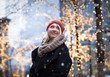 Winter portrait of young attractive woman with holiday lights an