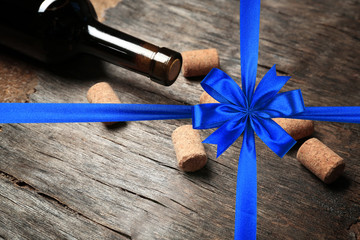 Canvas Print - Corks and bottle of wine on wooden table. Festive ribbon bow on background. Holiday celebration concept.