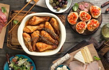 Poster - Baked chicken legs with variety of snacks on wooden table