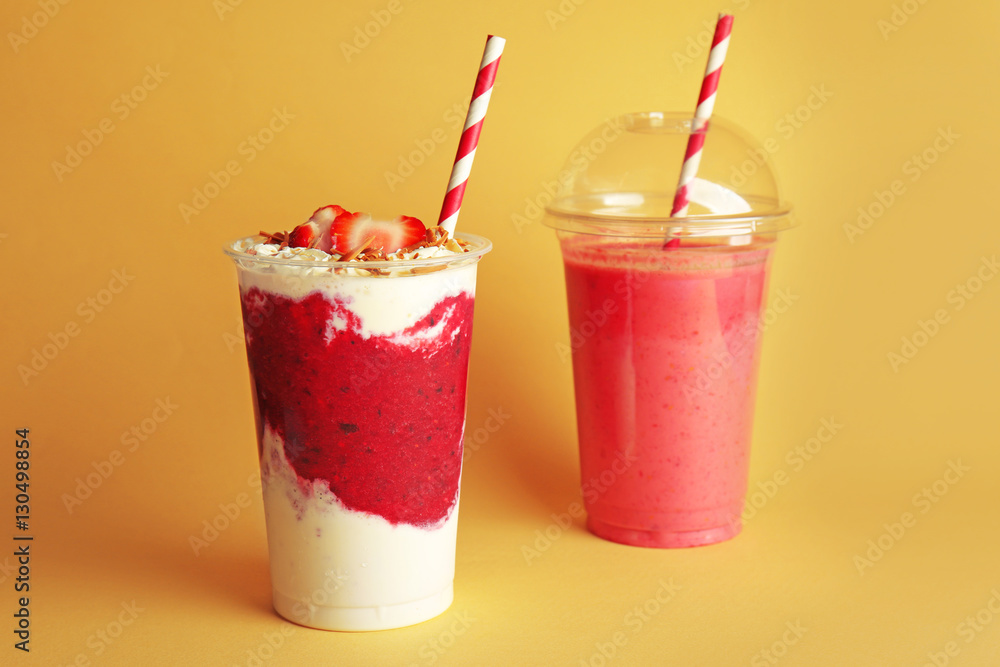 Delicious strawberry cocktails in plastic cups on yellow background