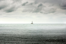 Single Lone Boat In Deep Sea And Heavy Overcast Clouds