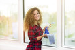 © Addoro - Smiling young woman cleaning the window.