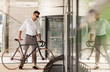 © Syda Productions - young man parking his bicycle on city street