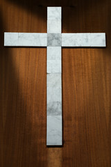 Wall Mural - White Marble Cross on a Wooden Background