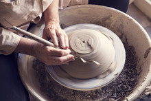 Midsection Of Woman Molding Clay On Potter's Wheel