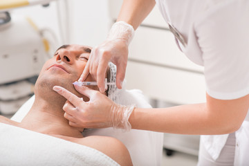 Skillful doctor injecting botox into human chin