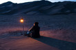 © Cavan Images - Rear view of man sitting on sand with illuminated lantern