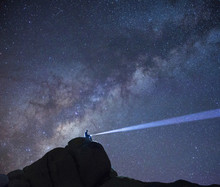 Scenic View Of Hiker With Illuminated Torch Against Starry Sky