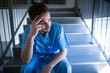 © WavebreakMediaMicro - Tensed male nurse sitting on staircase