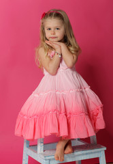 Portrait of baby posing on chair. Pink background