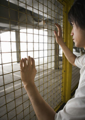 Wall Mural - Man looking through chainlink fence